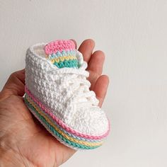 a hand holding a crocheted shoe in it's palm