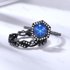 a ring with blue stone surrounded by black and white diamonds on a white tablecloth