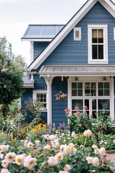 a blue house with lots of flowers in the front yard