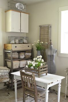 a white table and chairs in a room with some vases on top of it