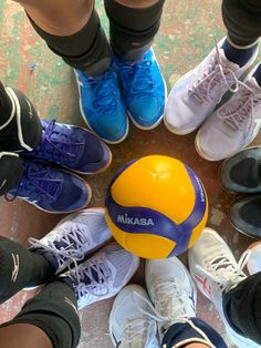 a group of people standing in a circle with a ball on top of their feet