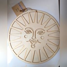 a wooden sun face hanging on the side of a refrigerator door with a tag attached to it