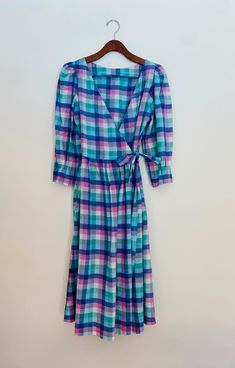 Vintage madras check wrap dress size 4. Fit and flare with A-line skirt bottom hitting below the knee. V neckline and capulet sleeve. Sleeves are 3/4 length with pleated effect at cuff. Fabric ties at waist that weave through insert holes to wrap and tie for closure. Two side insert pockets. Brand is Mati Sport. Believe it to be from the late 70s/early 80s. Measures 43.5 inches length and 17 in from underarm to underarm. 100% cotton. Made in India. Dress Clothes For Women, A Line Skirt, A Line Skirts, Fit And Flare, Wrap Dress, Dress Outfits, Size 4, Angeles, Bathing Beauties