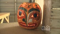 a carved pumpkin sitting on top of a table next to a wooden bench and wall