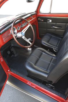 the interior of an old red car with black leather seats