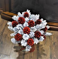 a vase filled with red and white flowers on top of a wooden floor next to a fireplace