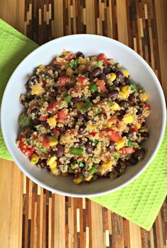 a white bowl filled with black beans and corn on top of a green towel next to a