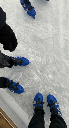 two people in blue shoes standing on an ice rink