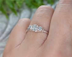 a woman's hand holding a three stone ring