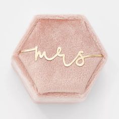 the word mrs is written in gold on a pink velvet hexagonal ring holder