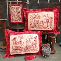 three red and white embroidered pillows with farm fresh designs on them next to a sewing machine