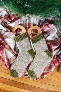 two pairs of knitted christmas stockings sitting on top of a plaid blanket