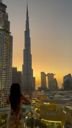 a woman standing on top of a tall building looking at the cityscape in the distance