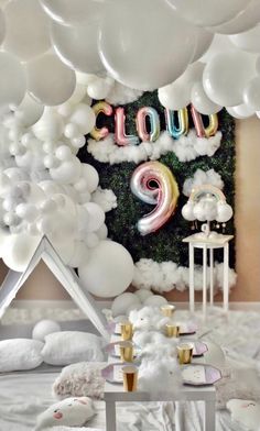 a room filled with lots of white balloons and some decorations on the wall above it