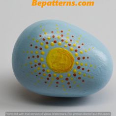 an easter egg with yellow and red dots painted on it's side, sitting in front of a white background