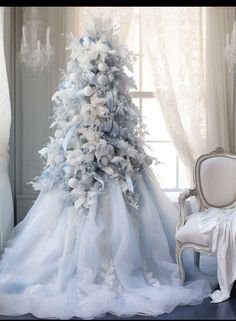 a white and blue christmas tree sitting next to a chair