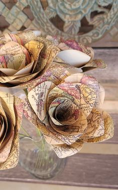 two paper roses are in a vase filled with water and other things to make it look like they have been made out of books