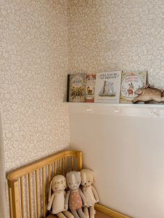 three stuffed animals sitting on top of a wooden crib in a room with wallpaper