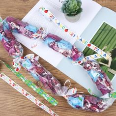 some candy wrapped in cellophane and tied to ribbons on a table with succulents