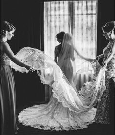 two women in dresses and veils are looking at another woman's wedding dress