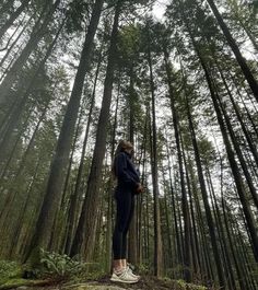 a woman standing in the middle of a forest