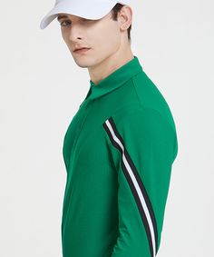 a young man wearing a green shirt and white hat with black stripes on the side