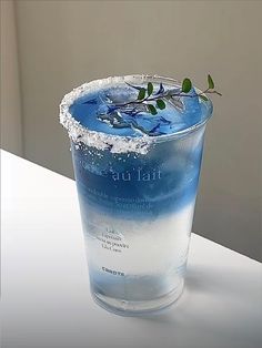 there is a blue drink in the glass with ice and water on it's rim