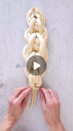 two hands are working on an art project with dough braids in the shape of a human head