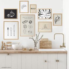 a kitchen with white cabinets and pictures on the wall