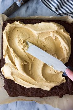 someone is spreading frosting on top of a brownie in a pan with a knife