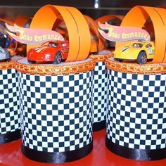 some toy cars are sitting on top of checkered cups with orange ribbon around them