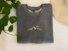 These unisex sweatshirts are the perfect way to get cozy and warm on a chilly day! Or to get as a gift for someone you love!  Made from 50% cotton and 50% polyester. This sweatshirt is super soft and comes in 3 sizes! - S - M - L and in 3 colors - Green - White - Gray A sweet mountain scene with a sun coming up behind it is embroidered on the front-center of the the sweatshirt.  When ordering choose the color and size of your sweatshirt and we will have it ready in 1-3 days!  When ordering stick Heather Grey Embroidered Logo Sweatshirt For Winter, Heather Grey Winter Sweatshirt With Embroidered Logo, Winter Heather Grey Sweatshirt With Embroidered Logo, Gray Embroidered Logo Sweatshirt For Winter, Cozy Winter Sweatshirt With Embroidered Logo, Winter Gray Sweatshirt With Embroidered Logo, Gray Winter Sweatshirt With Embroidered Text, Gray Mountain, Nature Embroidery