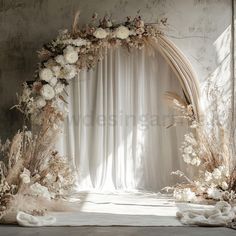 an arch decorated with flowers and feathers in front of a white drapeed curtain