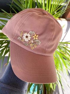 a pink hat with flowers on it sitting next to a potted plant