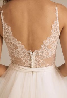 the back of a woman's wedding dress with lace and tulle on it