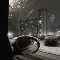 rain is falling on the windshield of a car as it drives down a city street