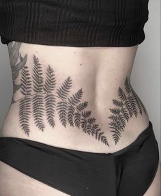 a woman's lower back tattoo with fern leaves on her stomach and bottom part