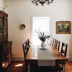 a dining room table with flowers in a vase on it