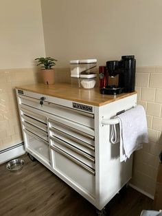 there is a white tool cabinet with many drawers on it and a coffee maker next to it