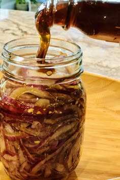 a jar filled with pickled onions on top of a wooden cutting board