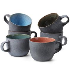 four different colored coffee mugs stacked on top of each other