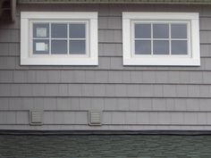 two windows on the side of a gray house