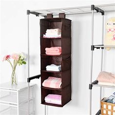 an ironing rack holds folded towels and blankets in the corner of a room next to a white wall