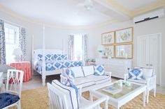 a living room filled with white furniture and blue and white decor on top of a rug