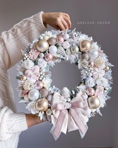 a woman holding a christmas wreath with ornaments on it and the words believe decor above it