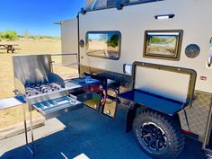 an off - road camper trailer is parked on the side of the road near a picnic table