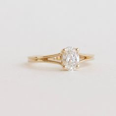 a yellow gold engagement ring with an oval cut diamond in the center, on a white background