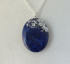 This pendant features delicate silver leaf work on a natural stone. The metal is treated with a micro-crystalline wax to preserve and protect the silver work. The chain measures 18 inches. The pendant is approximately 30 x 40 mm. Silver Lapis Lazuli Round Pendant Jewelry, Silver Lapis Lazuli Round Pendant Necklace, Silver Lapis Lazuli Gemstone Necklace, Oval Pendant Lapis Lazuli Jewelry Gift, Silver Necklace With Round Lapis Lazuli Pendant, Oval Lapis Lazuli Silver Jewelry, Oval Silver Lapis Lazuli Jewelry, Silver Lapis Lazuli Necklaces With Spiritual Style, Silver Jewelry With Oval Lapis Lazuli