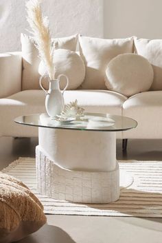 a white couch sitting next to a glass table on top of a rug