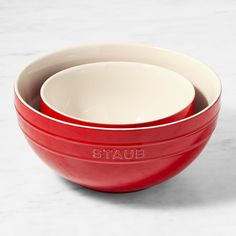 three red and white bowls sitting on top of each other in front of a marble counter